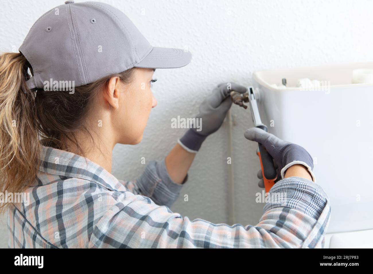 female plumber repairing toilet flush Stock Photo