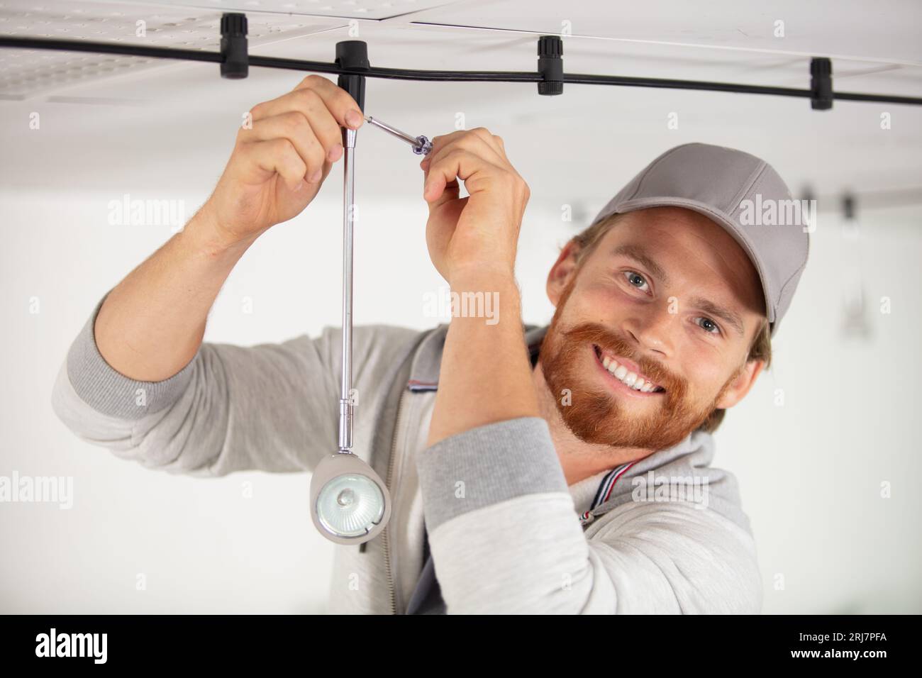 young electrician repairing ceiling light Stock Photo