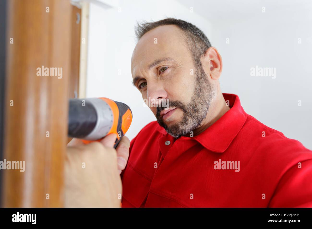 hardworker man drilling wooden frame Stock Photo