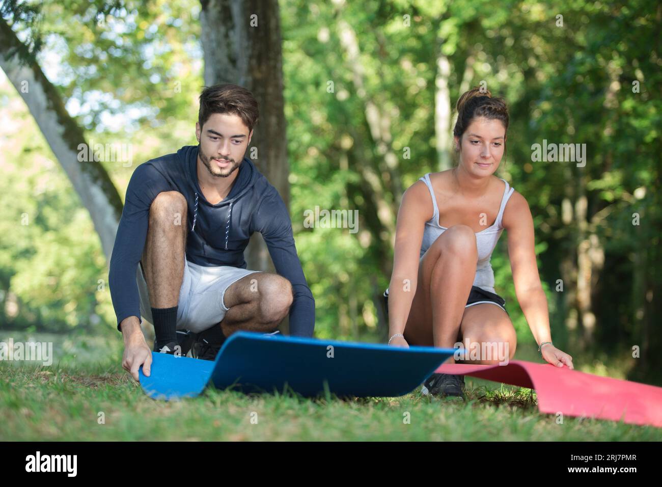 man and woman laying mats on grass to exercise on Stock Photo Alamy