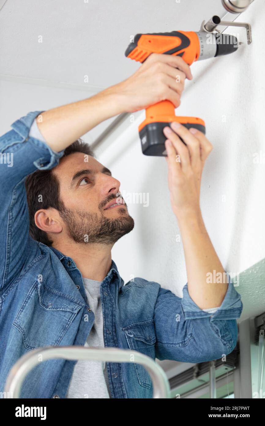 man drilling a hole in a ceiling Stock Photo