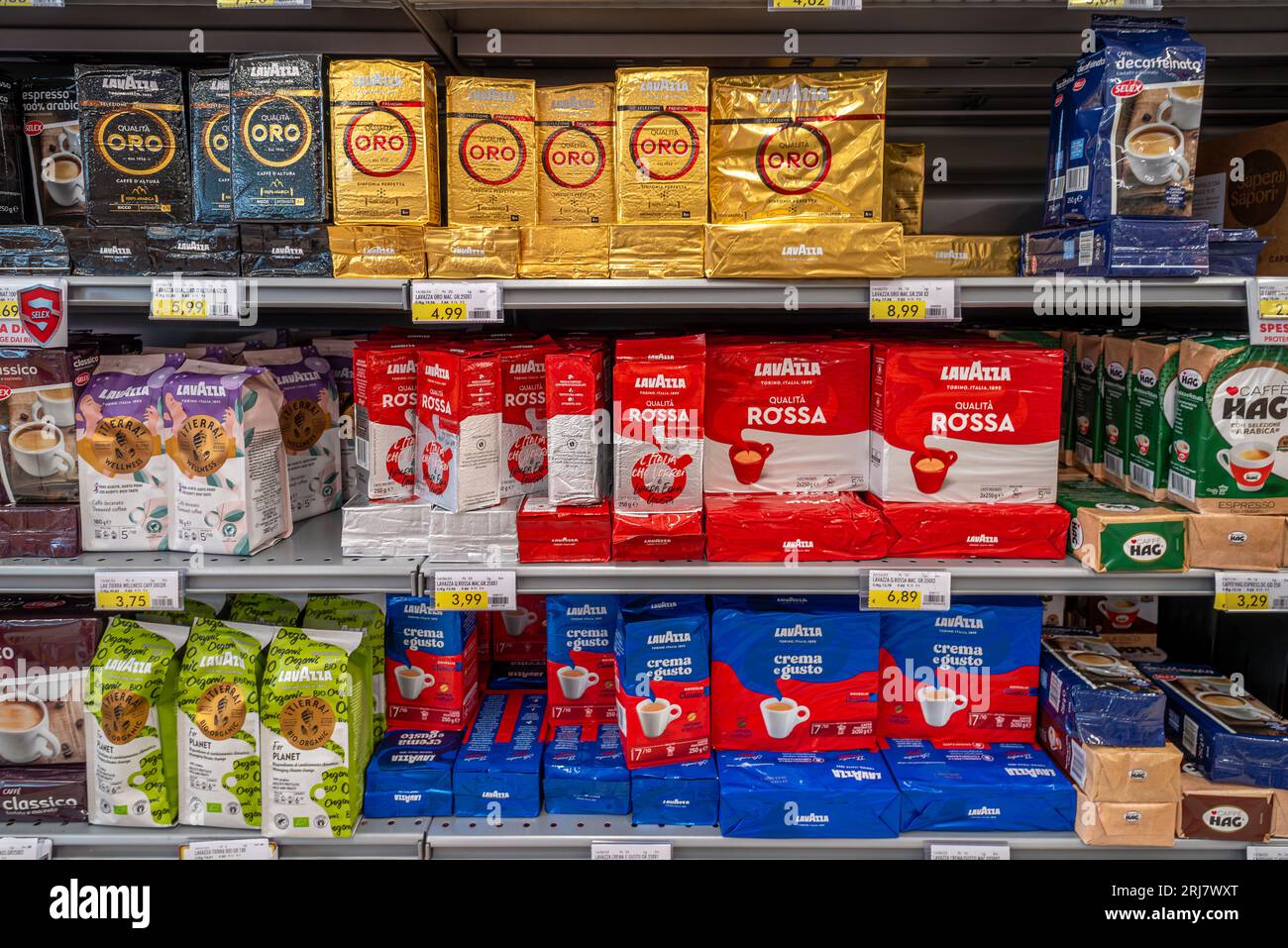 Italy - August 14, 2023: Lavazza coffee in packs of various types and colors displayed on shelf for sale in Italian supermarket Stock Photo