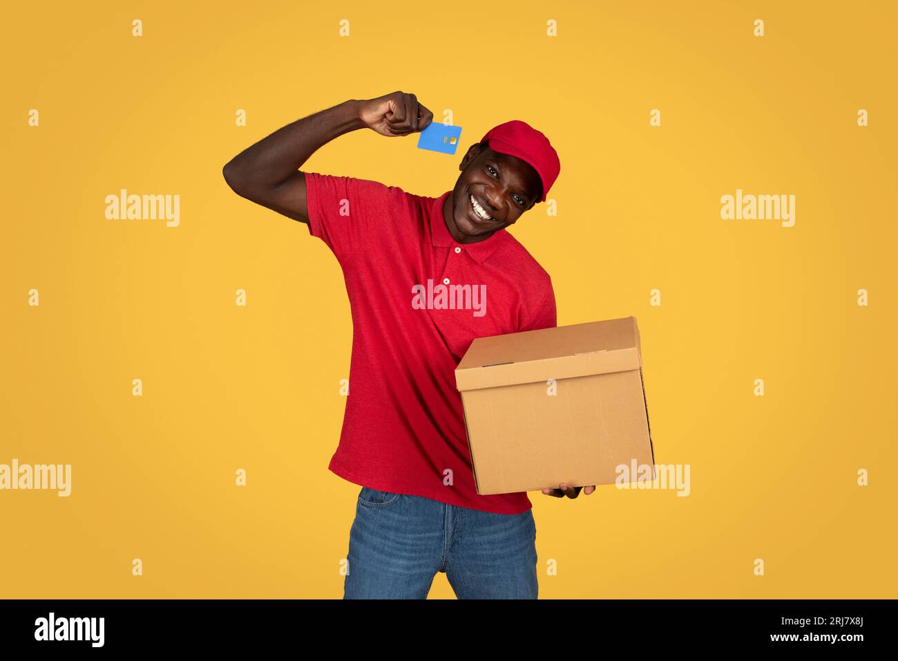 Cheerful millennial african american guy courier hold box, recommends credit card Stock Photo