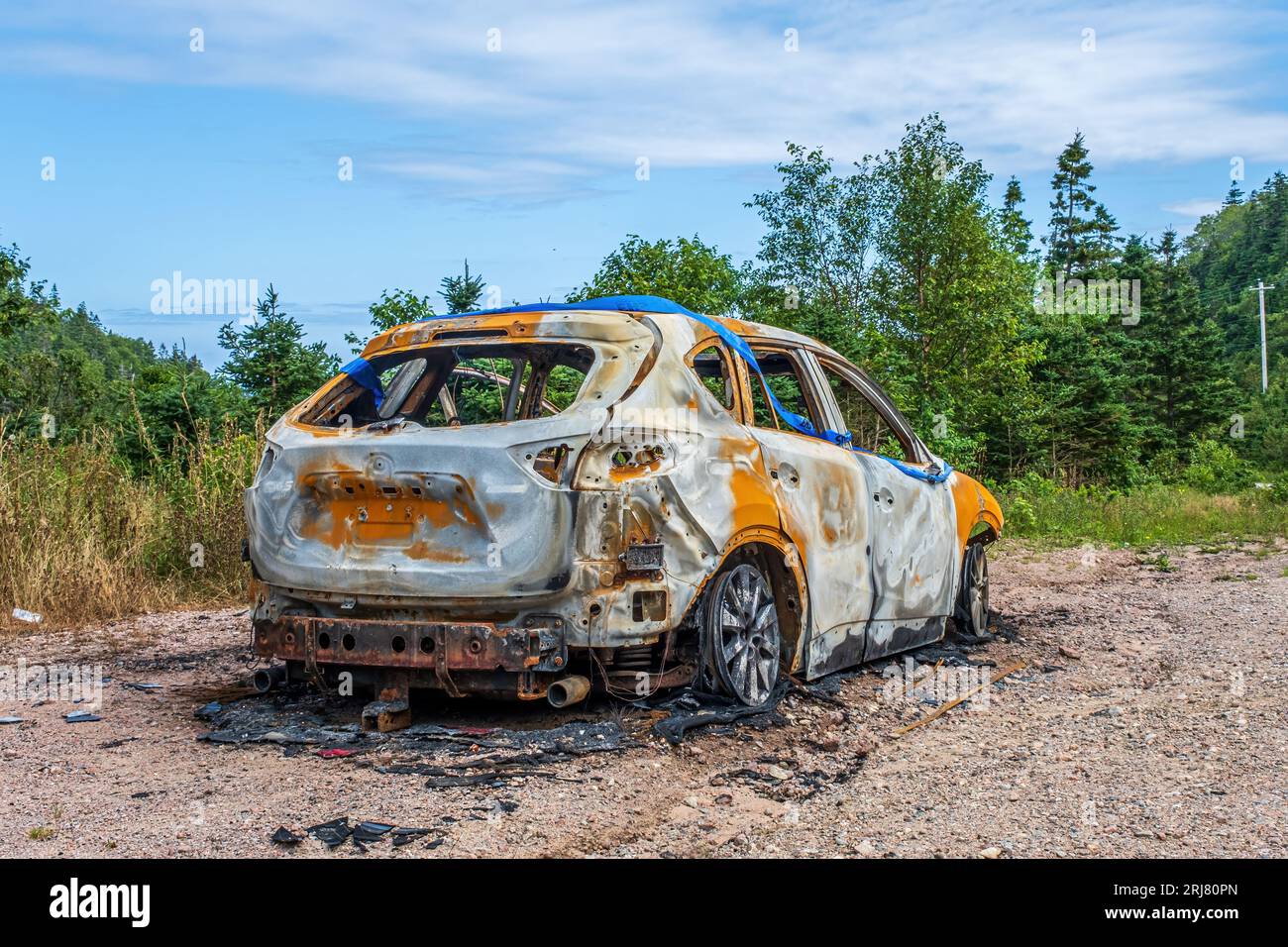 Automobile obviously destroyed by fire sitting by the side of the road.  Unknown cause. Stock Photo