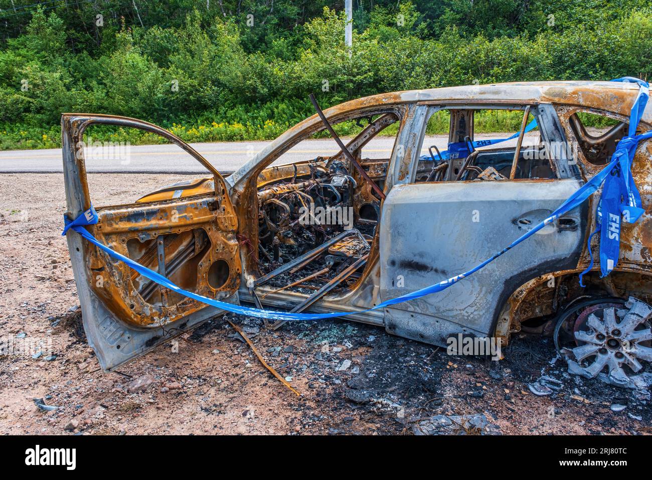 Automobile obviously destroyed by fire sitting by the side of the road.  Unknown cause. Stock Photo