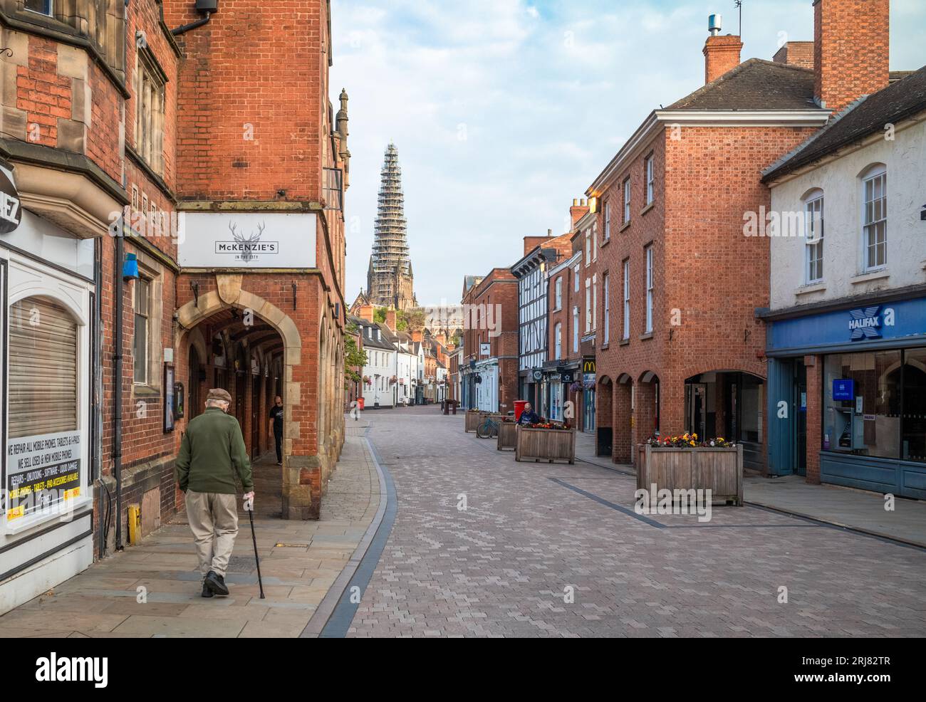 An elderly man walks down Conduit Street at sunrise with a view of