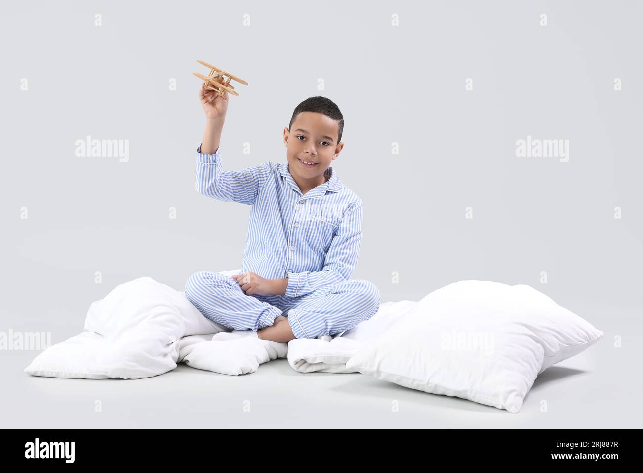 Little African-American boy with wooden plane and soft blanket on light background Stock Photo