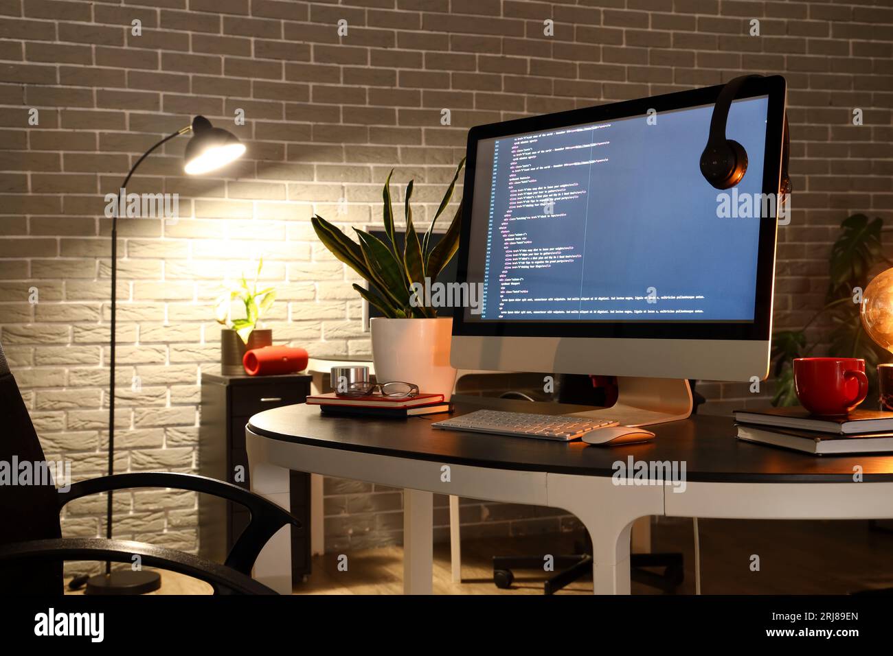 Programmer's workplace with computer in dark office Stock Photo