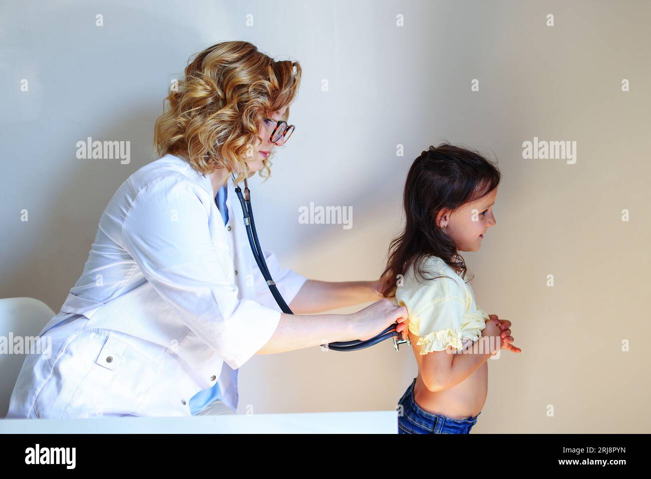 Doctor examining back of 8 year-old girl - Stock Image - C040/1357 -  Science Photo Library
