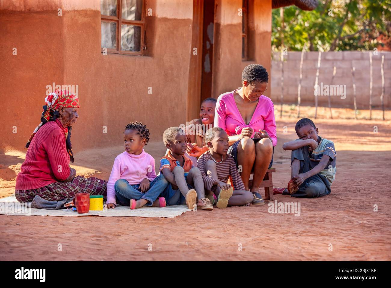 village african family sited in the yard in front of the house, three ...