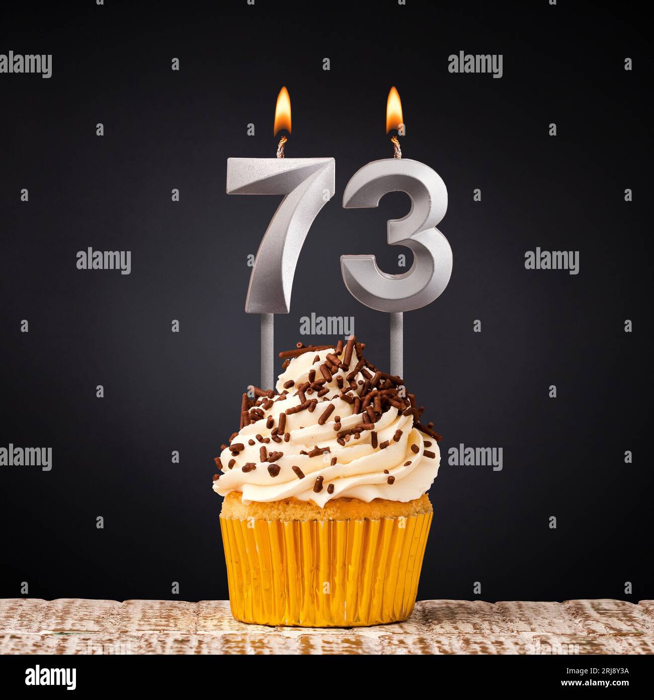 Birthday candle number 73 - Anniversary cupcake on black background Stock Photo