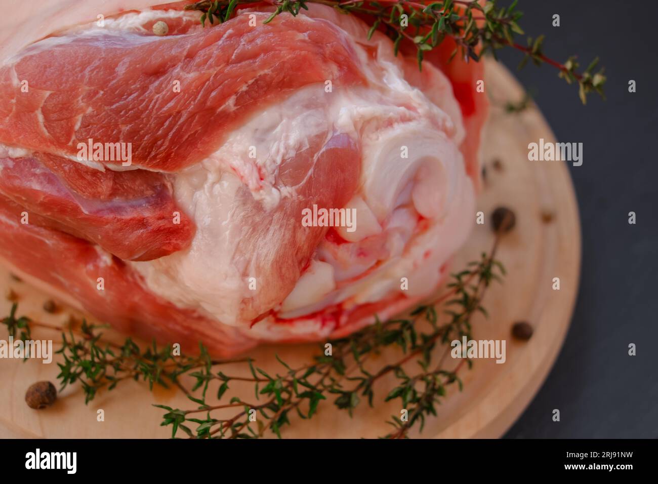 Pork knuckle.Farm organic meat. Pork meat on the bone, peppercorns, fresh thyme on a black slate background. Stock Photo