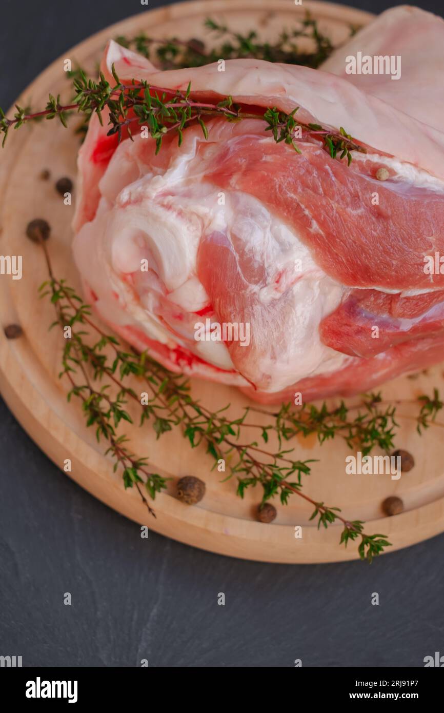 Pork knuckle.Farm organic meat. Pork meat on the bone, peppercorns, thyme on a black slate background. Stock Photo