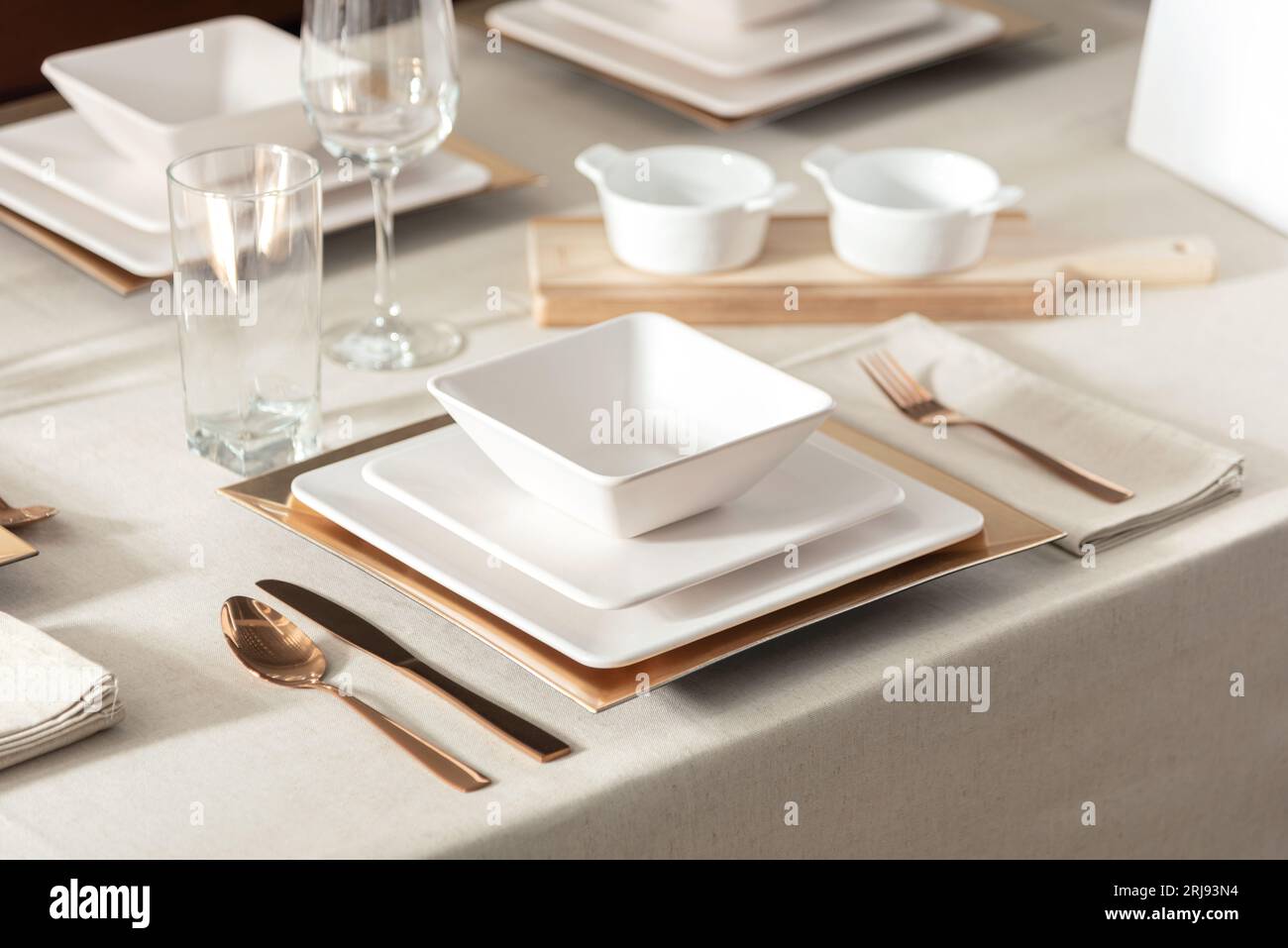 A white rectangular table with a variety of plates and glasses spread across its surface Stock Photo