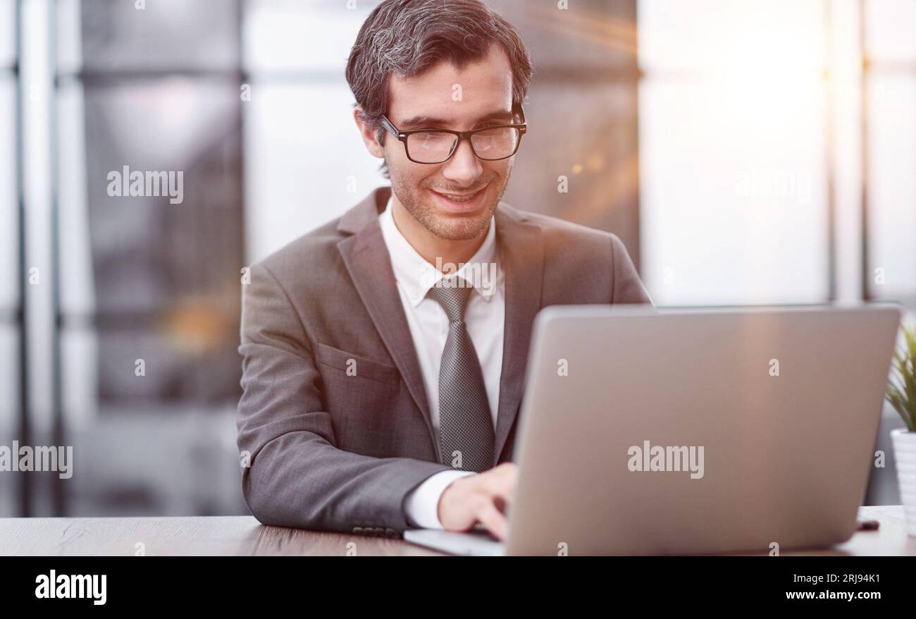 Smiling business man working on laptop at office. Stock Photo