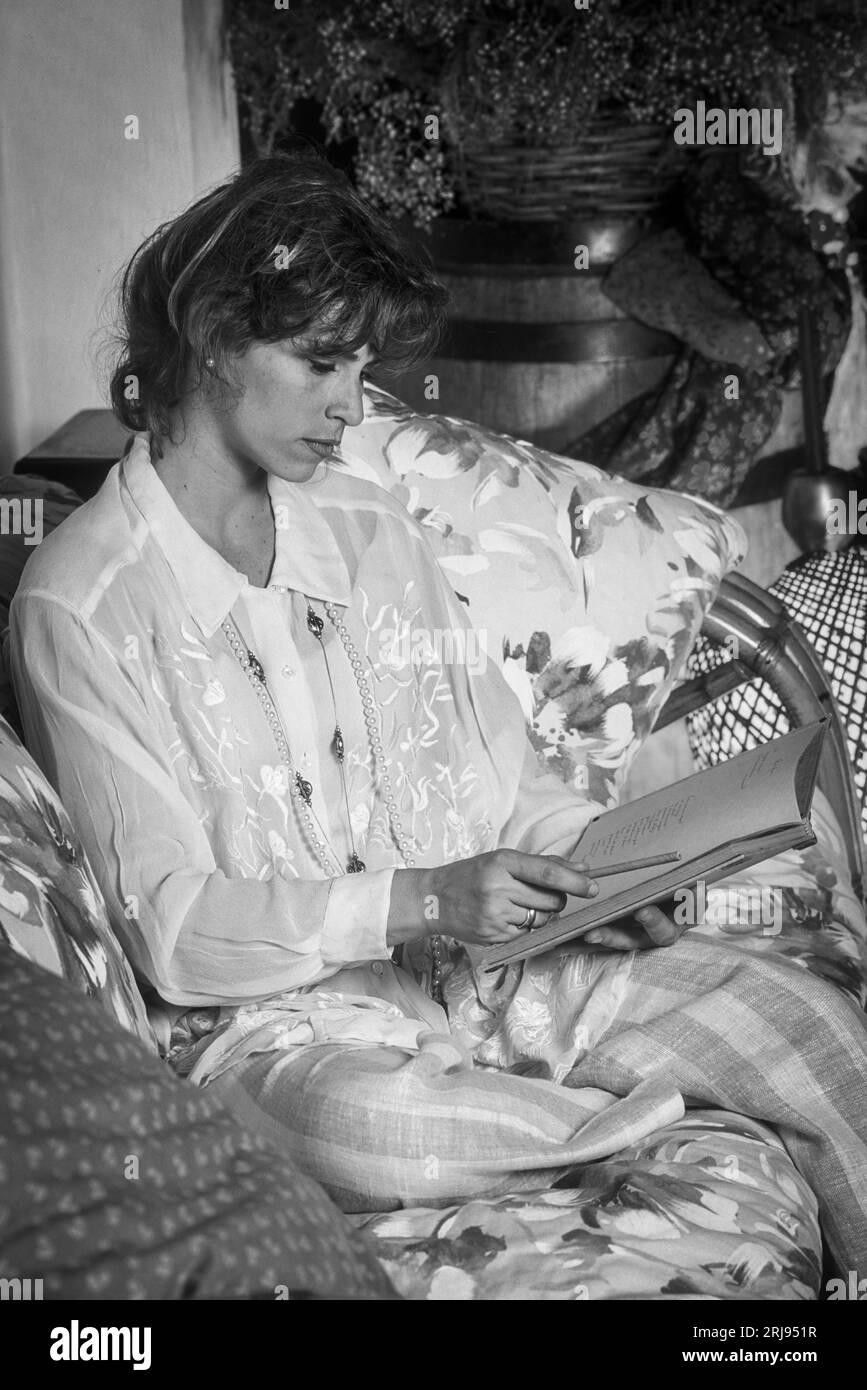 Young woman sitting in a sofa with a book Stock Photo