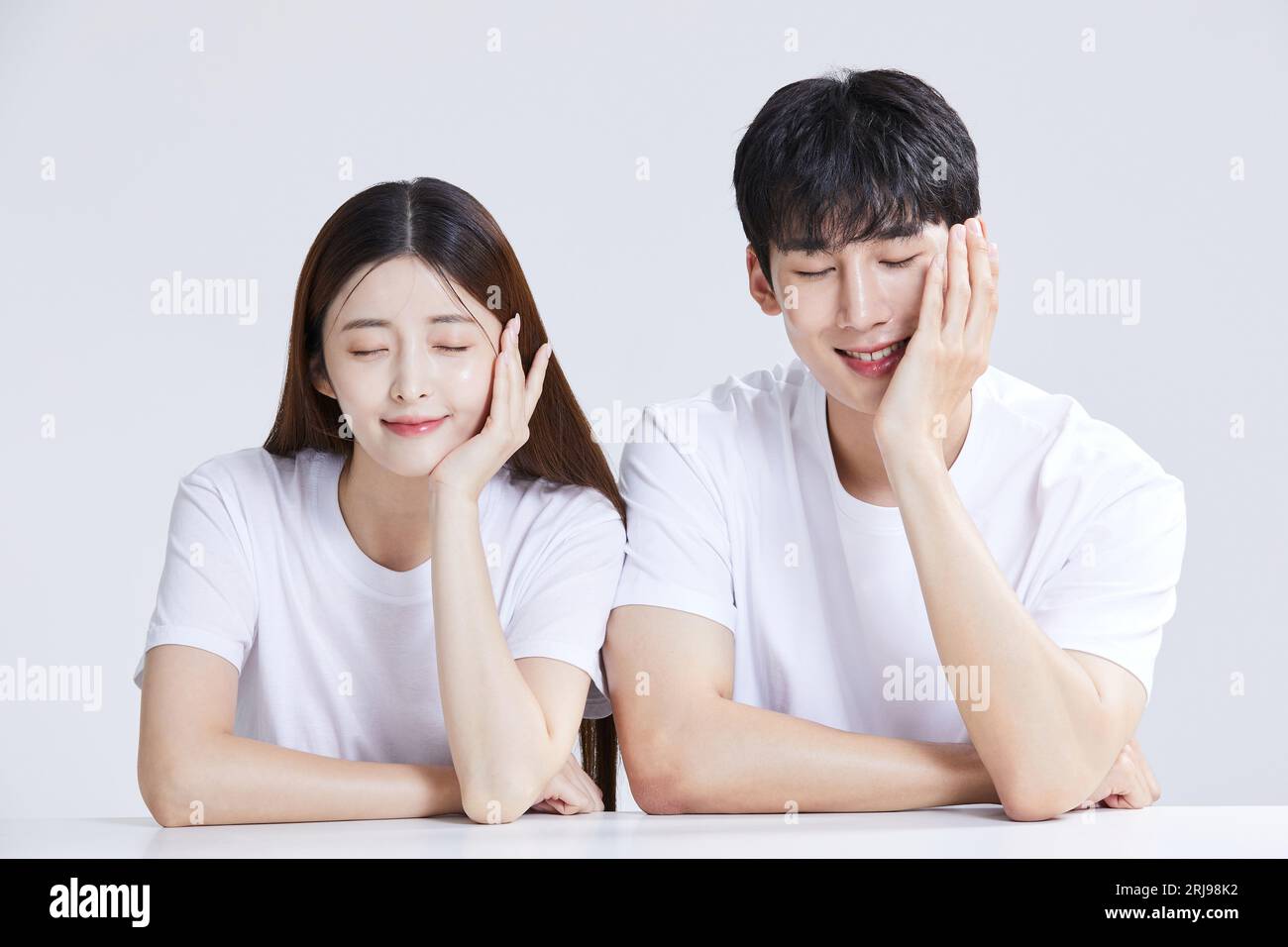 korean asian young couple sitting and resting their chins on hands Stock Photo