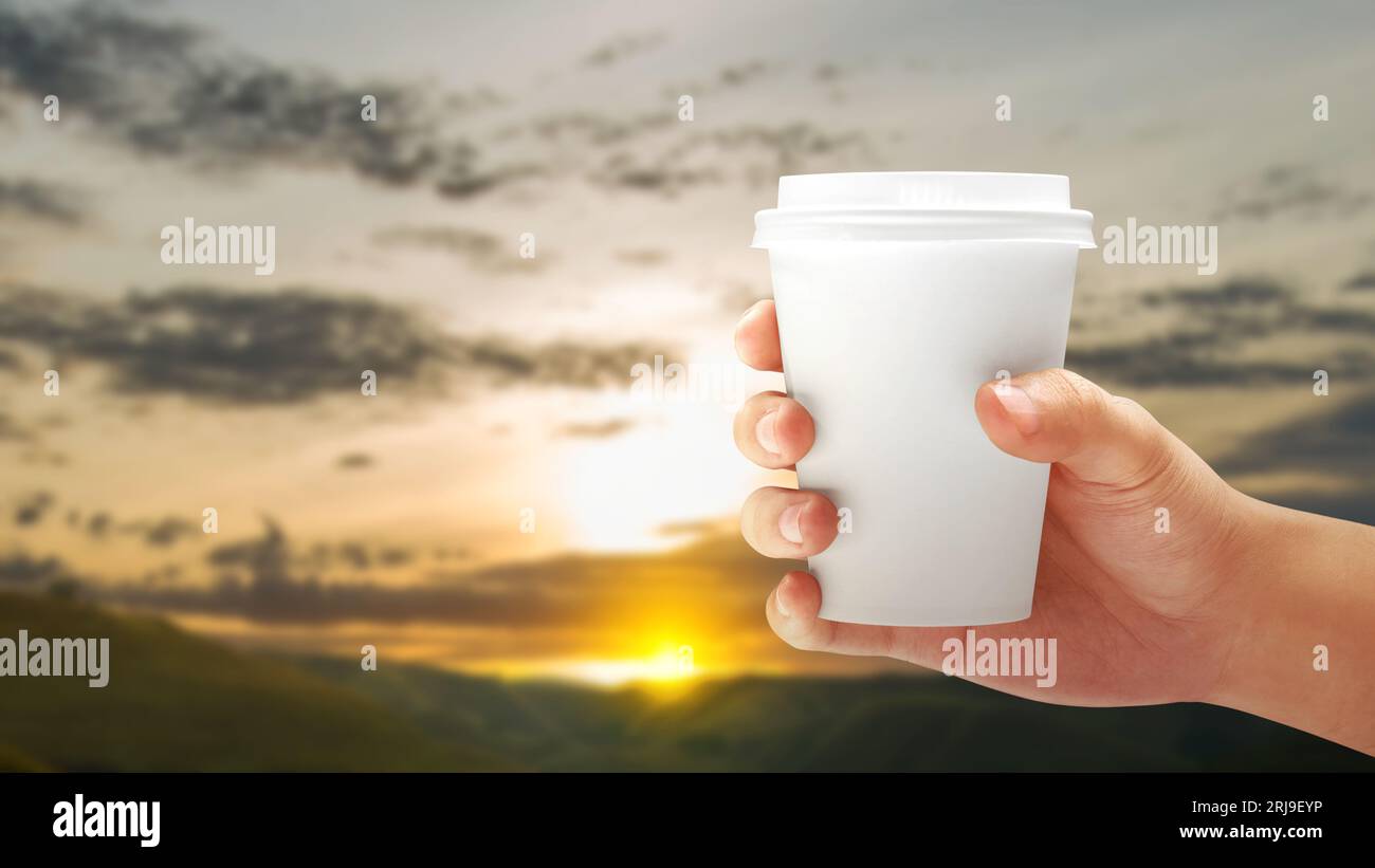 https://c8.alamy.com/comp/2RJ9EYP/a-human-hand-holding-cup-of-coffee-with-a-sunset-scene-background-international-coffee-day-concept-2RJ9EYP.jpg