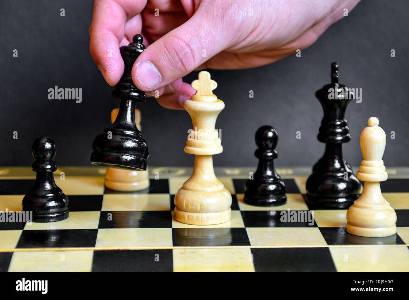 Chess player hand making move with white queen to checkmate