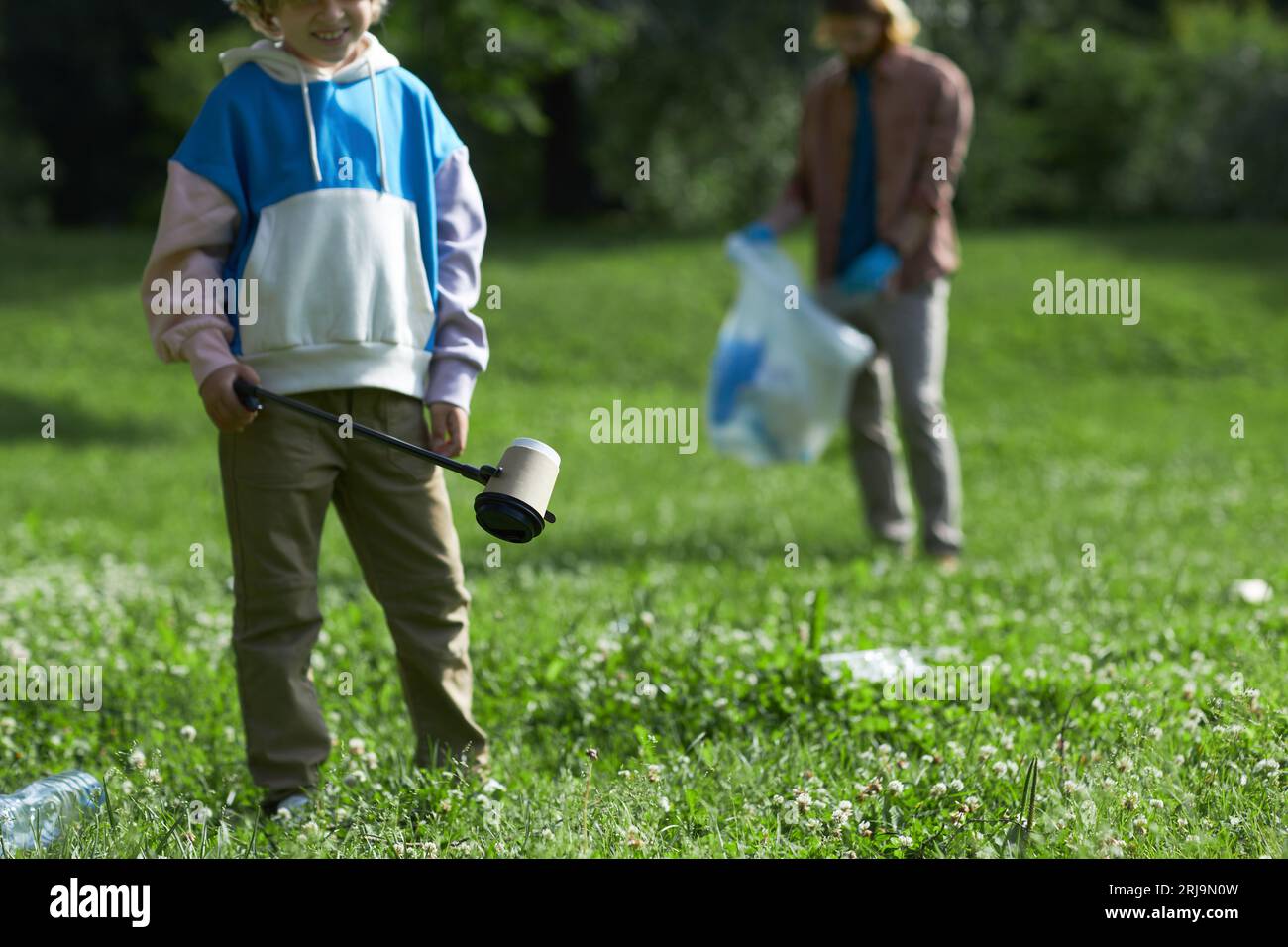 Closeup of little boy picking up trash in nature eco activist family