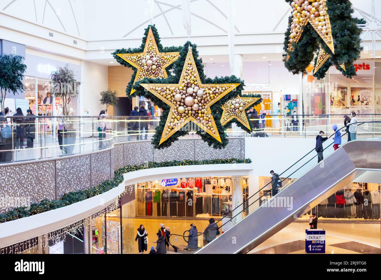escalator and christmas shopping mall interior, huge stars decor in new year holidays. Pavlodar, Kazakhstan - 01.17.2023 Stock Photo