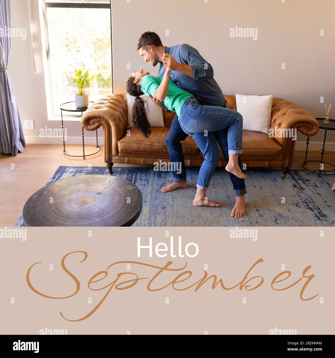 Composite of hello september text over caucasian couple dancing in living room Stock Photo