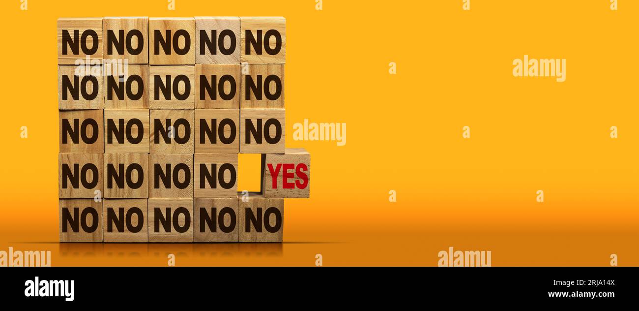 Stack of wooden blocks with text Yes or No. On a yellow and orange ...