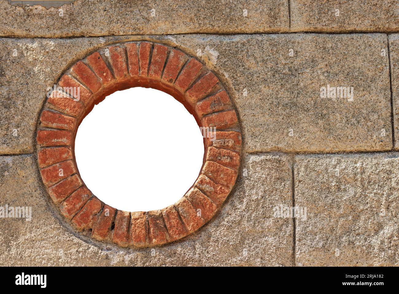 Close-up of a small round window with brick frame isolated on white background with copy space. La Spezia province, Liguria, Italy, Europe. Stock Photo