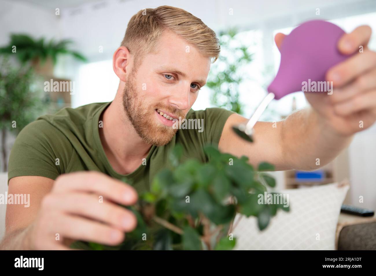 young gardener watering bonsai using sprinkler Stock Photo