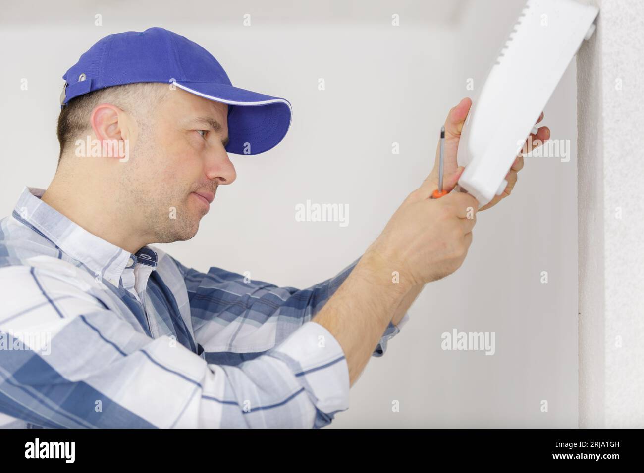 repairman standing and fixing device with screwdriver over walls Stock Photo