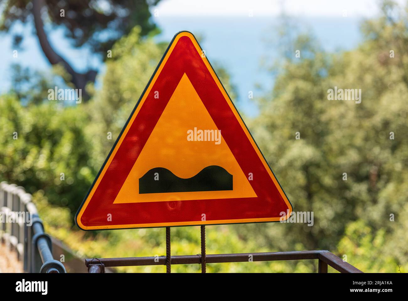 Triangular road sign of bumpy road. It is a danger sign that announces a deformed road, in bad condition, uneven or with irregular pavement. Stock Photo