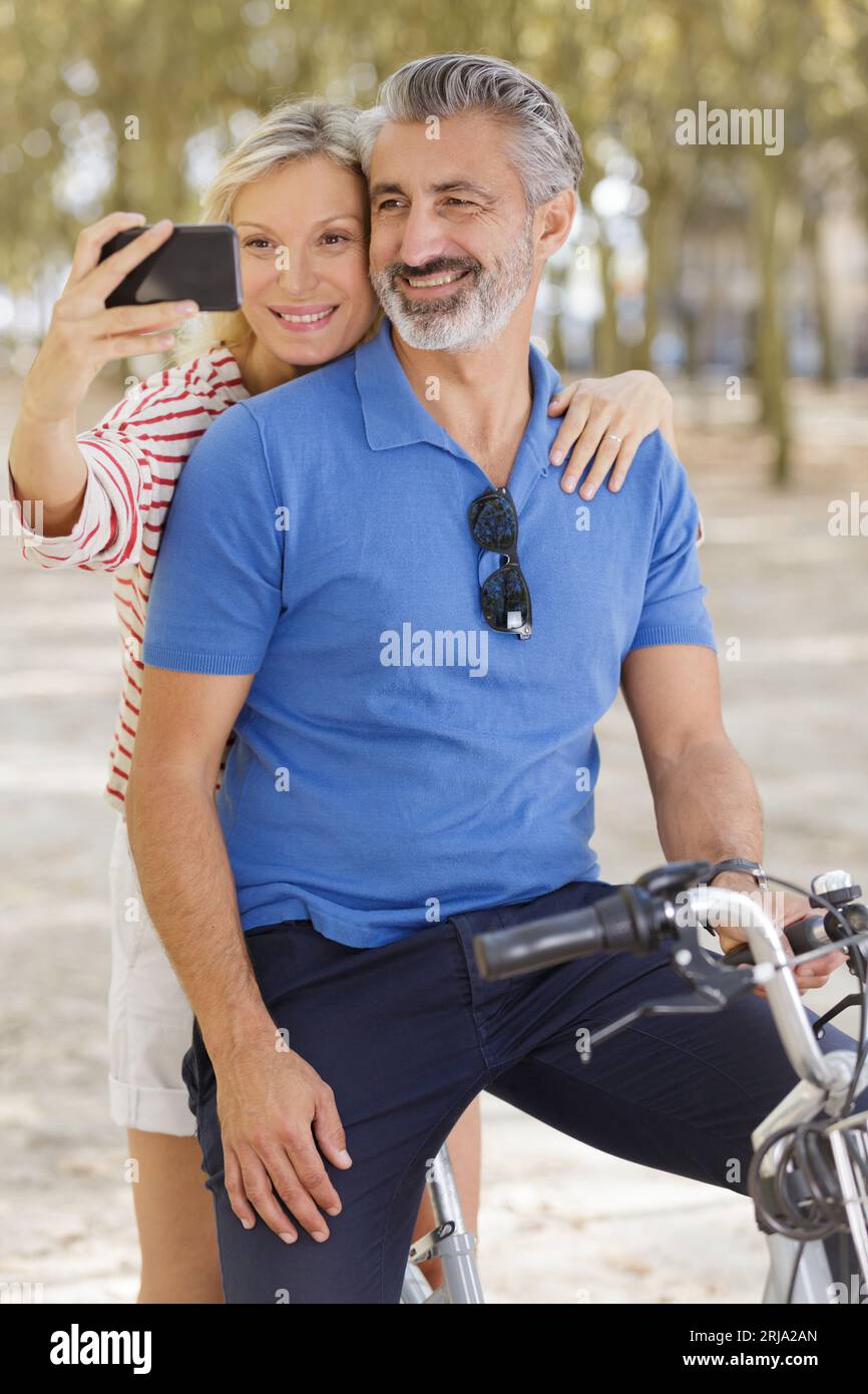 happy couple with bicycles taking selfie in the summer park Stock Photo