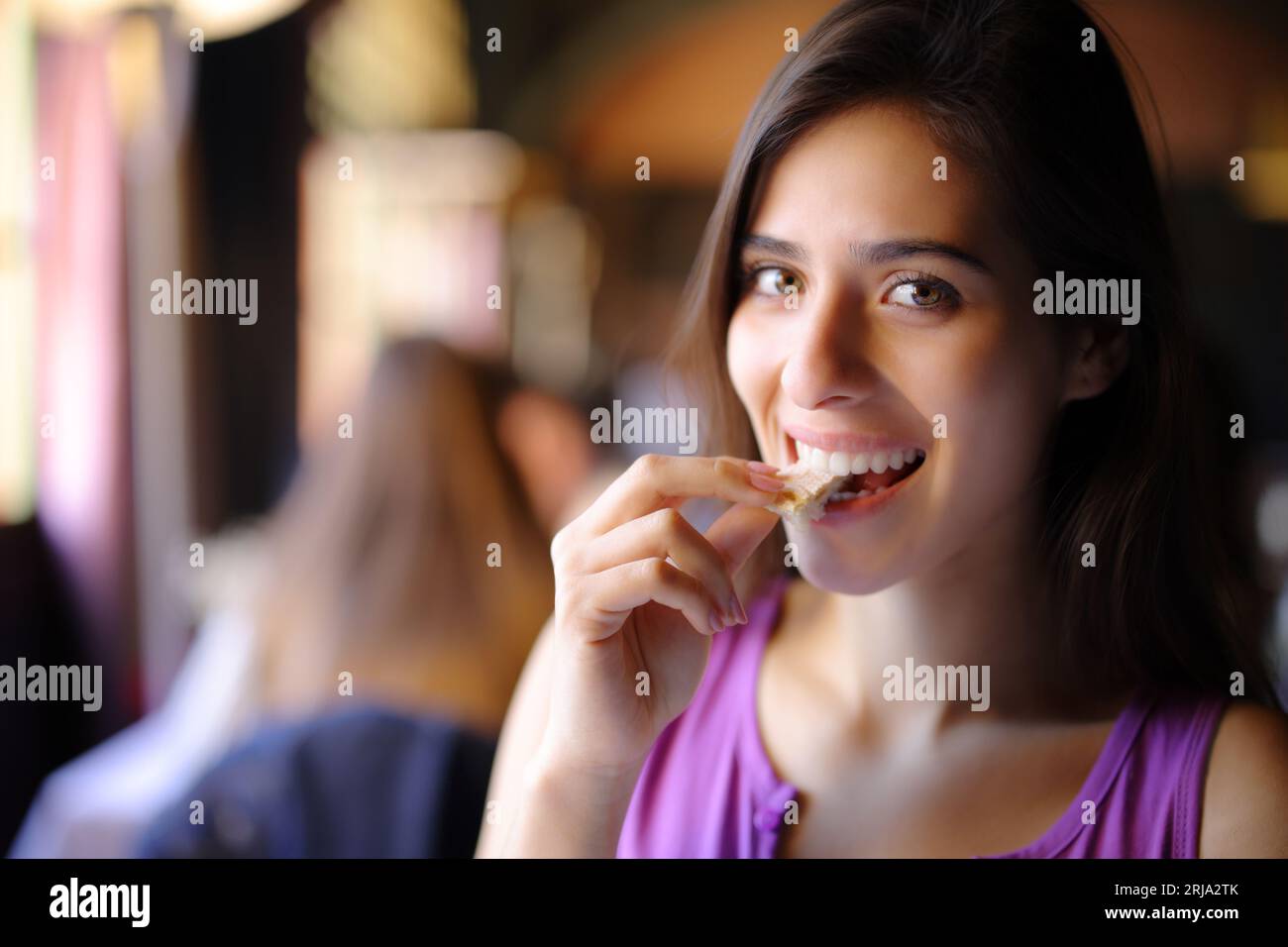 Happy beautiful restaurant customer eating bread looking at you Stock Photo