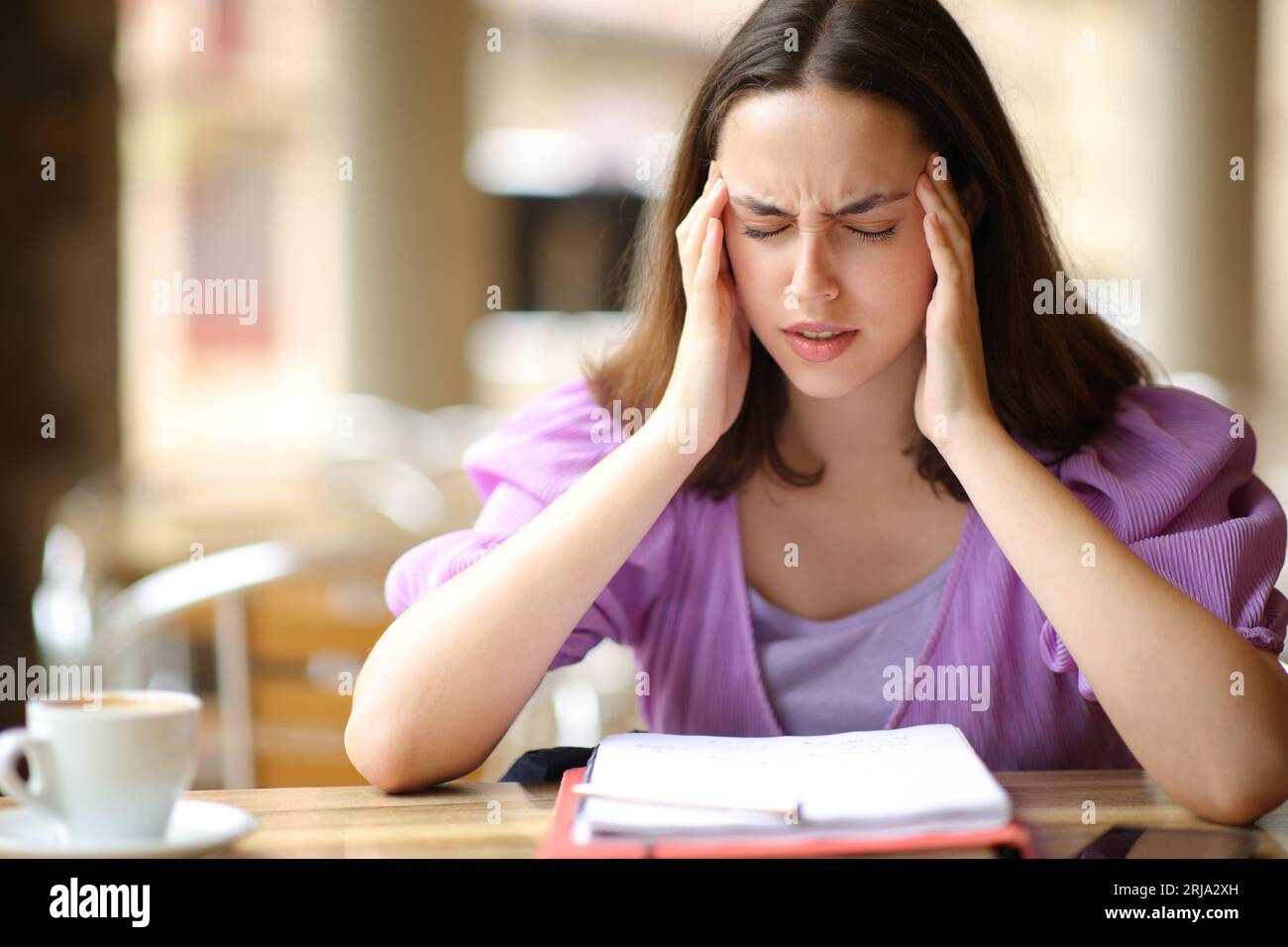 Student studying and suffering migraine in a bar terrace Stock Photo