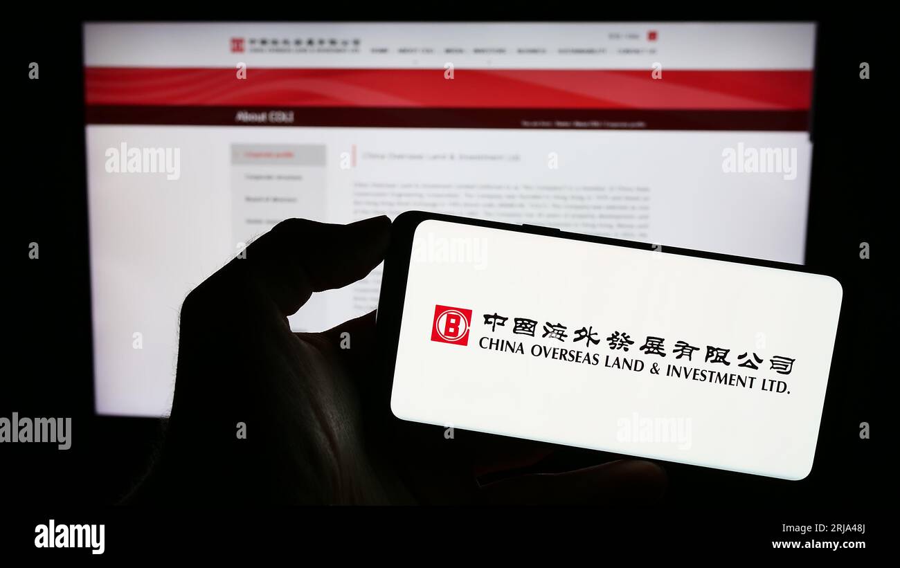 Person holding smartphone with logo of China Overseas Land and