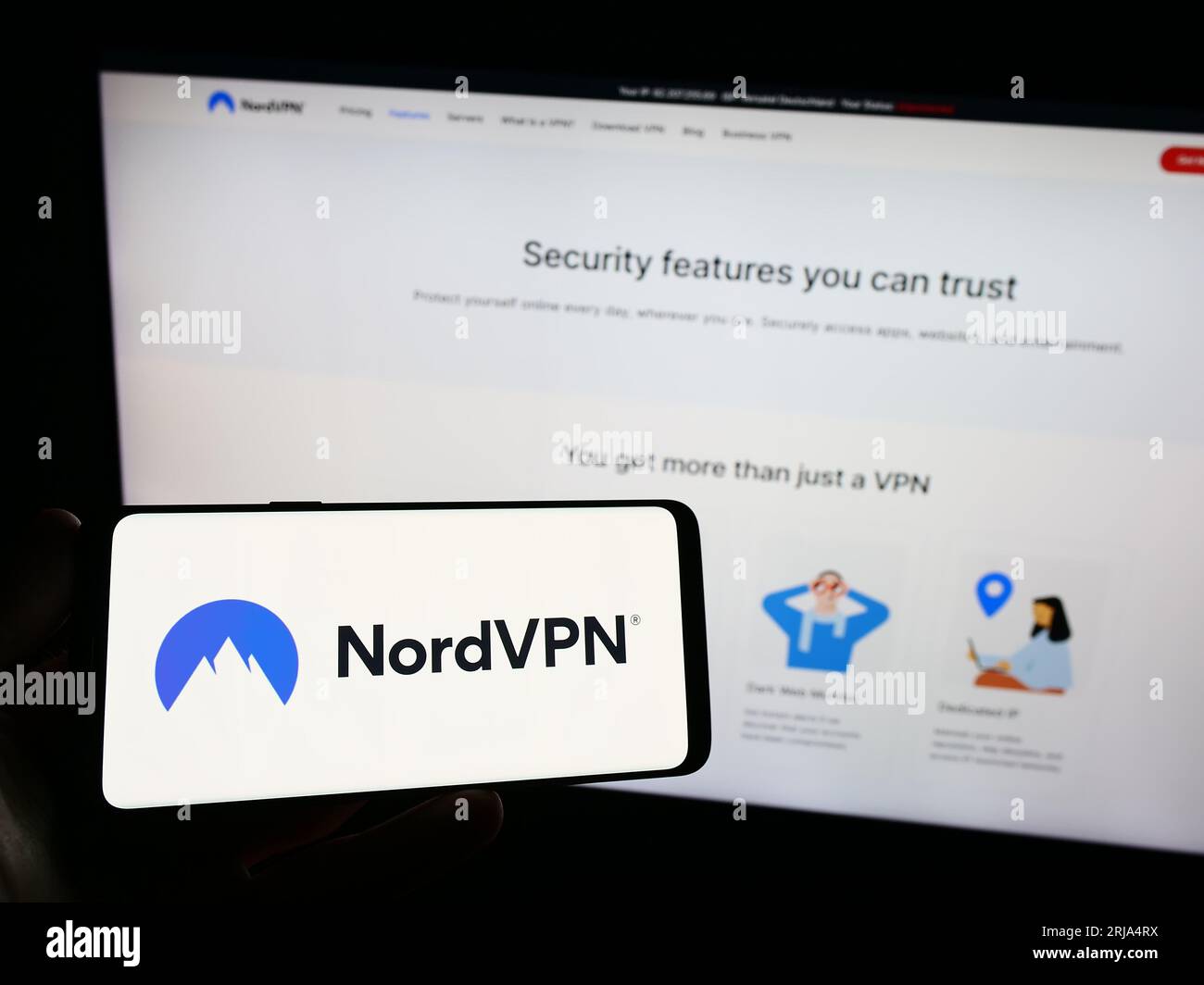 Person holding smartphone with logo of VPN service NordVPN (Nordsec Ltd.) on screen in front of website. Focus on phone display. Stock Photo