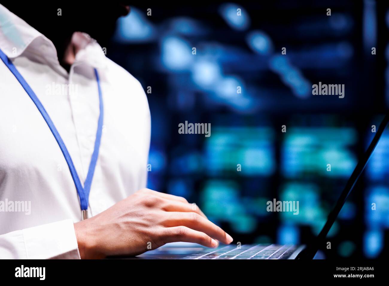 Specialist using laptop to do troubleshooting on data center mainframes with high computing power enabling hyperscale server hub to support demanding applications such as machine learning workloads Stock Photo