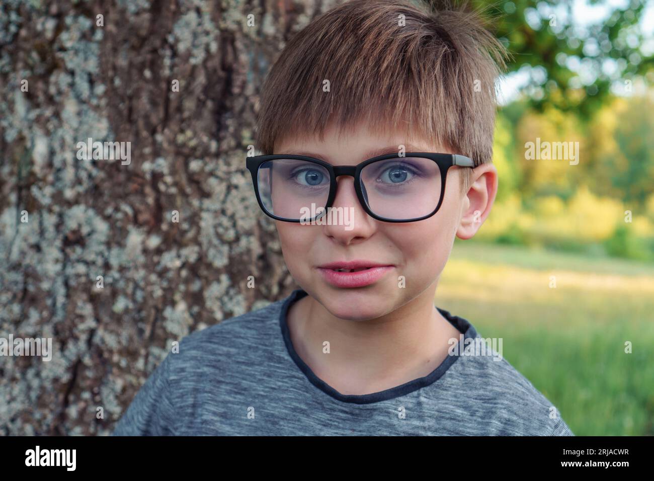 Portrait of loveable boy with blue eyes, in glasses wearing gray