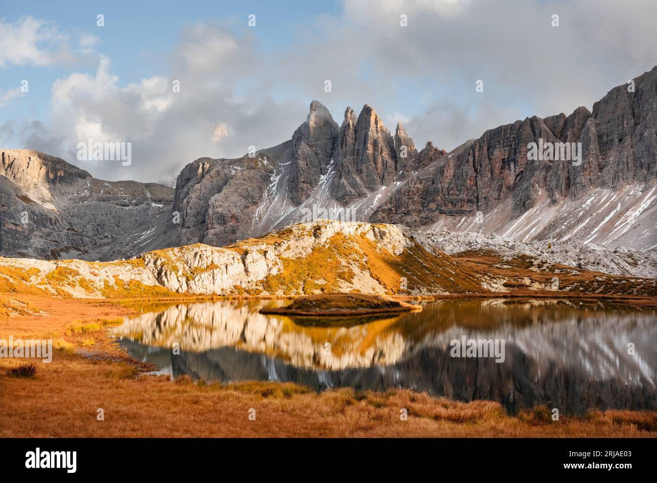 Clear turquoise water of alpine lake Piani in the Tre Cime Di Laveredo National Park, Dolomites, Italy. Picturesque landscape with snowy mountains, orange grass and small lake in autumn Dolomite Alps Stock Photo