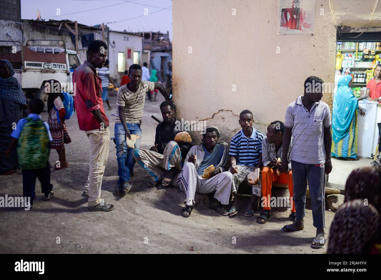 DJIBOUTI , Obock, from here ethiopian migrants try to cross bab el mandeb by boat to Yemen to go on to Saudi Arabia or Europe, group of young male ethiopian refugees at shop with bread / DSCHIBUTI, Obock, Meerenge Bab el Mandeb, mit Hilfe von Schleppern versuchen aethiopische Migranten hier nach Jemen ueberzusetzen, um weiter nach Saudi Arabien oder Europa zu gelangen, Gruppe aethiopischer Fluechtlinge, zweiter von links: Nema Mohammed Hassan (grau weiß gestreiftes T-Shirt) Stock Photo