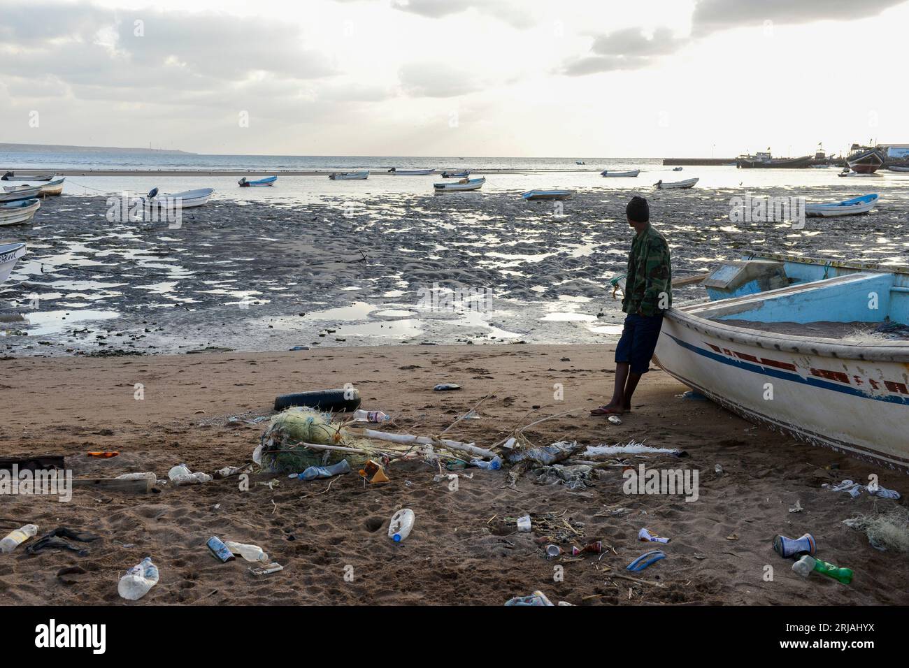 DJIBOUTI , Obock, from here ethiopian migrants try to cross bab el mandeb, red sea, gulf of aden by smuggler boats to Yemen to continue the journey to Saudi Arabia or Europe, ethiopian migrant looking to the sea / DSCHIBUTI, Obock, Meerenge Bab el Mandeb, mit Hilfe von Schleppern versuchen aethiopische Migranten hier über das Rote Meer nach Jemen ueberzusetzen, um weiter nach Saudi Arabien oder Europa zu gelangen Stock Photo