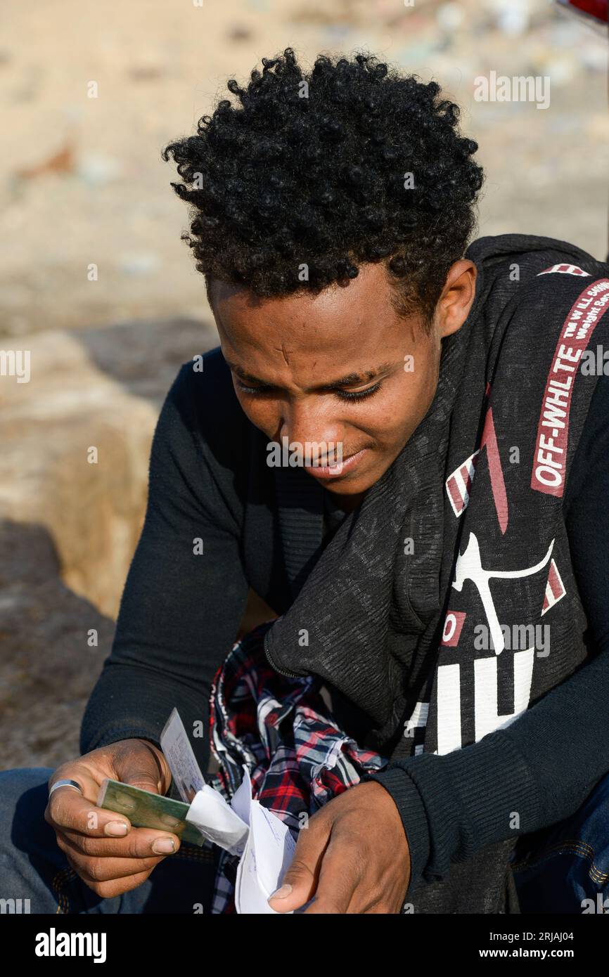 DJIBOUTI , Obock, from here ethiopian migrants try to cross bab el mandeb by boat to Yemen to go on to Saudi Arabia or Europe, ethiopian refugees from Tigray waiting outside the town for the smugglers, ethiopian orthodox christian with cross scar on the forehead / DSCHIBUTI, Obock, Meerenge Bab el Mandeb, mit Hilfe von Schleppern versuchen aethiopische Migranten aus Tigray hier nach Jemen ueberzusetzen, um weiter nach Saudi Arabien oder Europa zu gelangen, orthodoxer Christ mit auf der Stirn in die Haut eingeritztem Kreuz Stock Photo