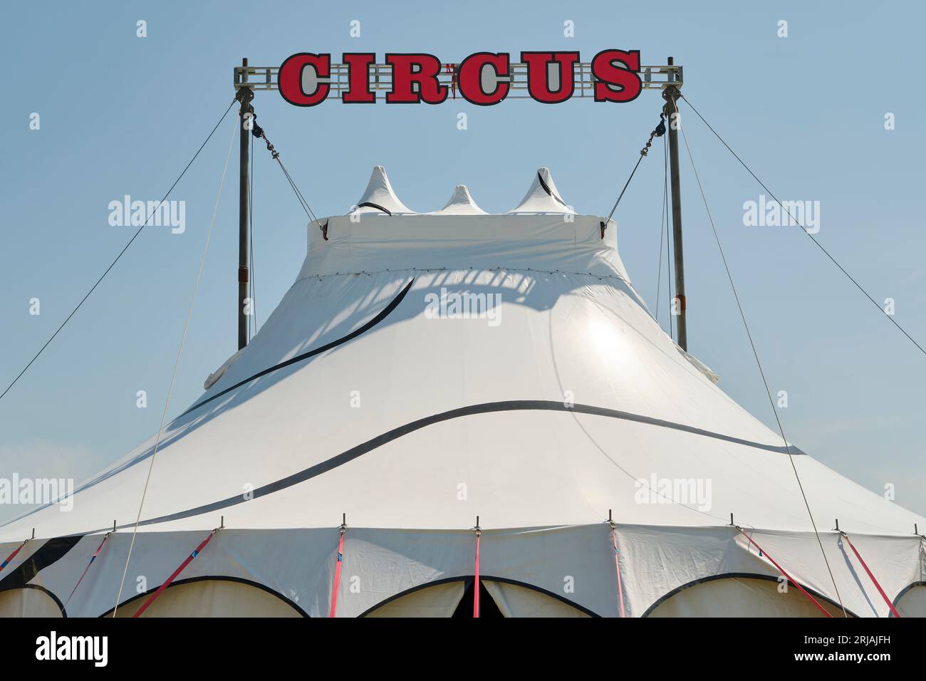 Small white circus tent with red characters against a blue sky. Stock Photo