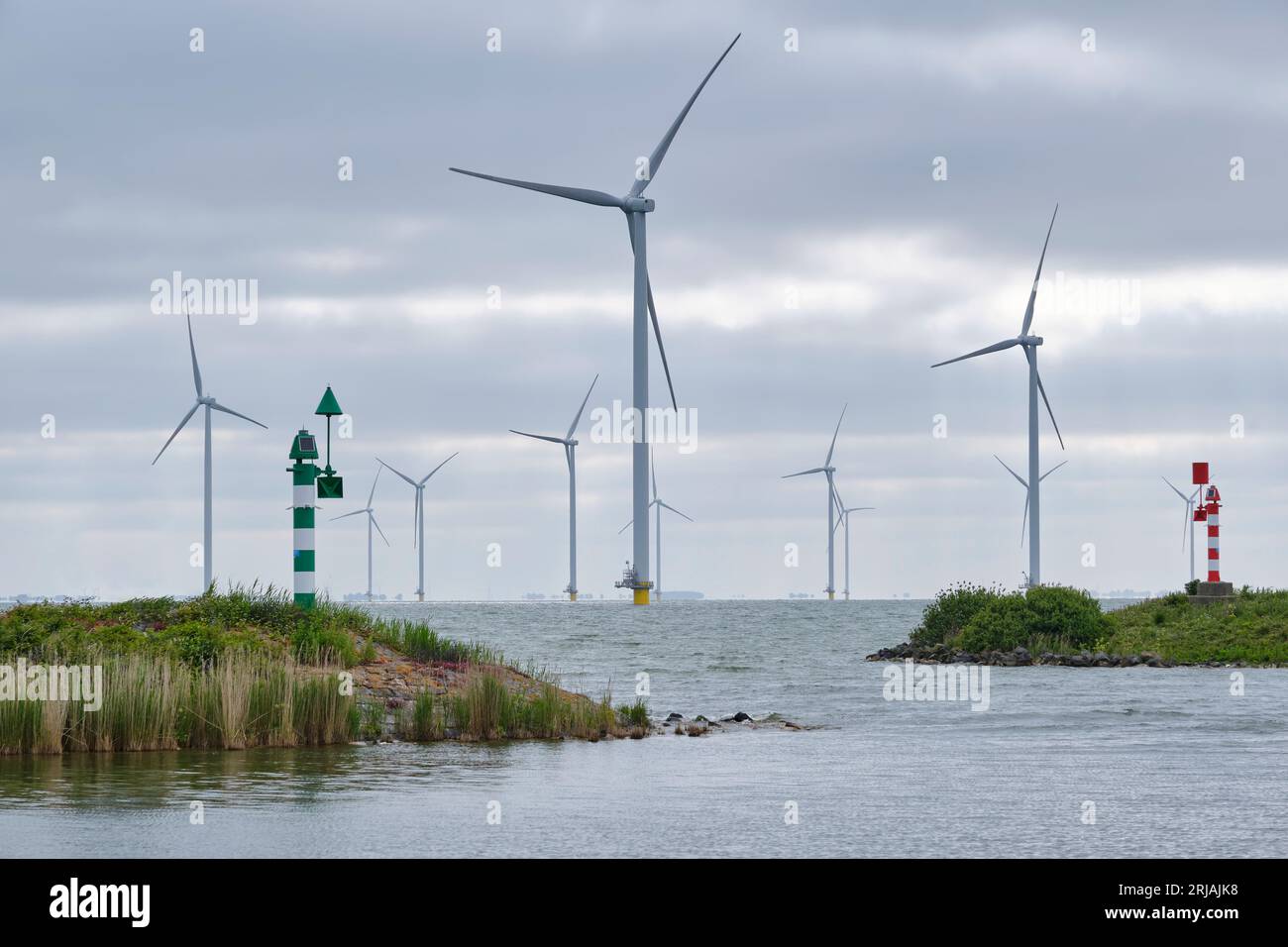 View of an offshore wind farm from the harbour in the early morning light. Windpark Fryslân was built in the IJsselmeer lake in the Netherlands Stock Photo