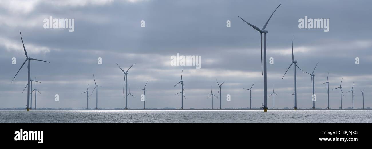 Panorama of an offshore wind farm from the harbour in the early morning light. Windpark Fryslân was built in the IJsselmeer lake in the Netherlands Stock Photo