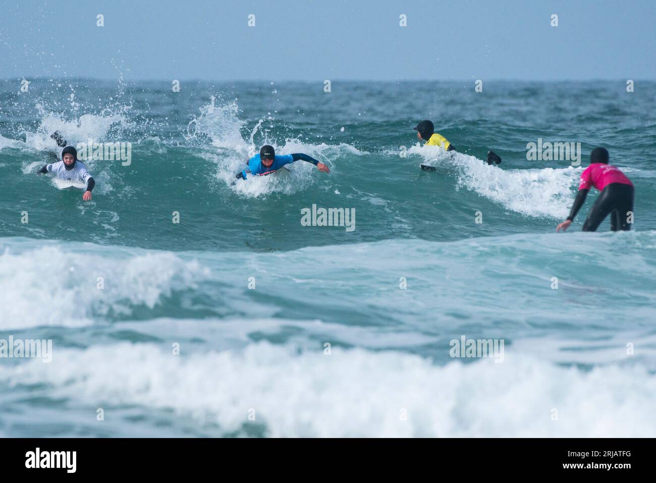 Young competitors riding a wave during the Rip Curl Grom Search surfing competition at Fistral in Newquay in Cornwall in the UK. Stock Photo