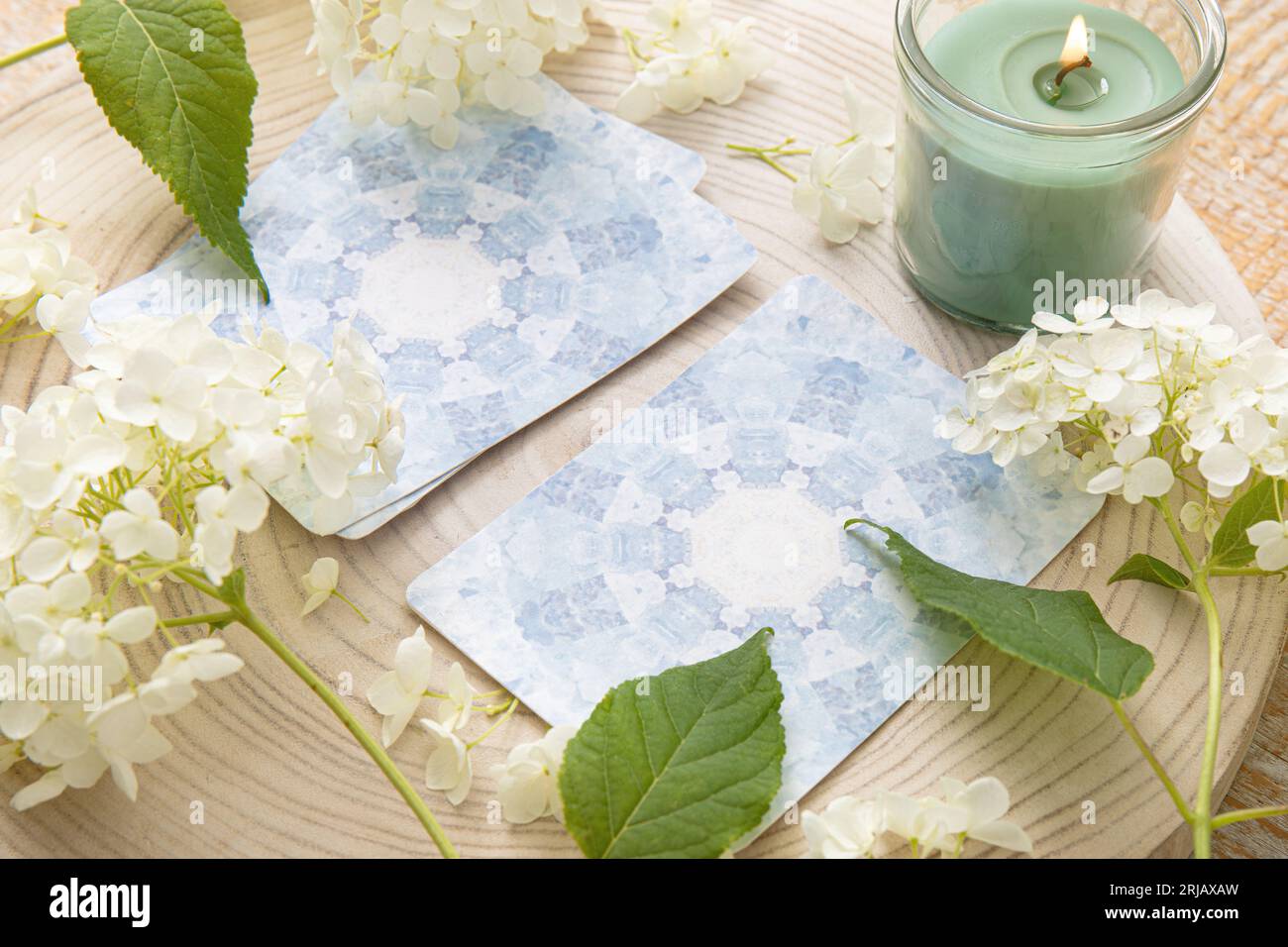 Deck with homemade divination Angel cards on wood table with hydrangea flower for decoration. Home indoors candle burning. Stock Photo