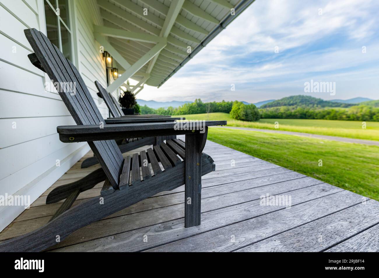 A wooden chair positioned on a veranda overlooking a grassy outdoor area Stock Photo