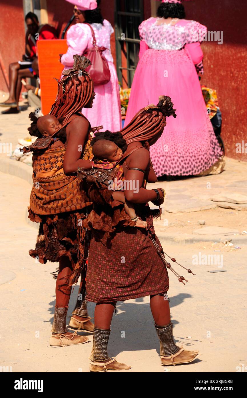 Himba women with their babies and herero women in the background