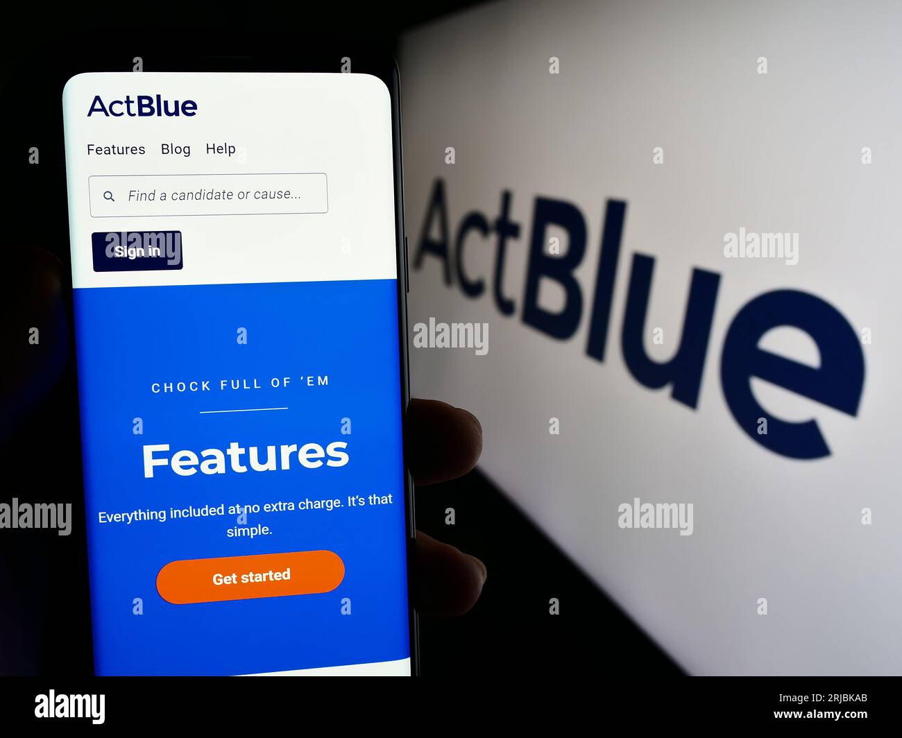 Person holding smartphone with website of fundraising organization ActBlue Charities Inc. on screen with logo. Focus on center of phone display. Stock Photo